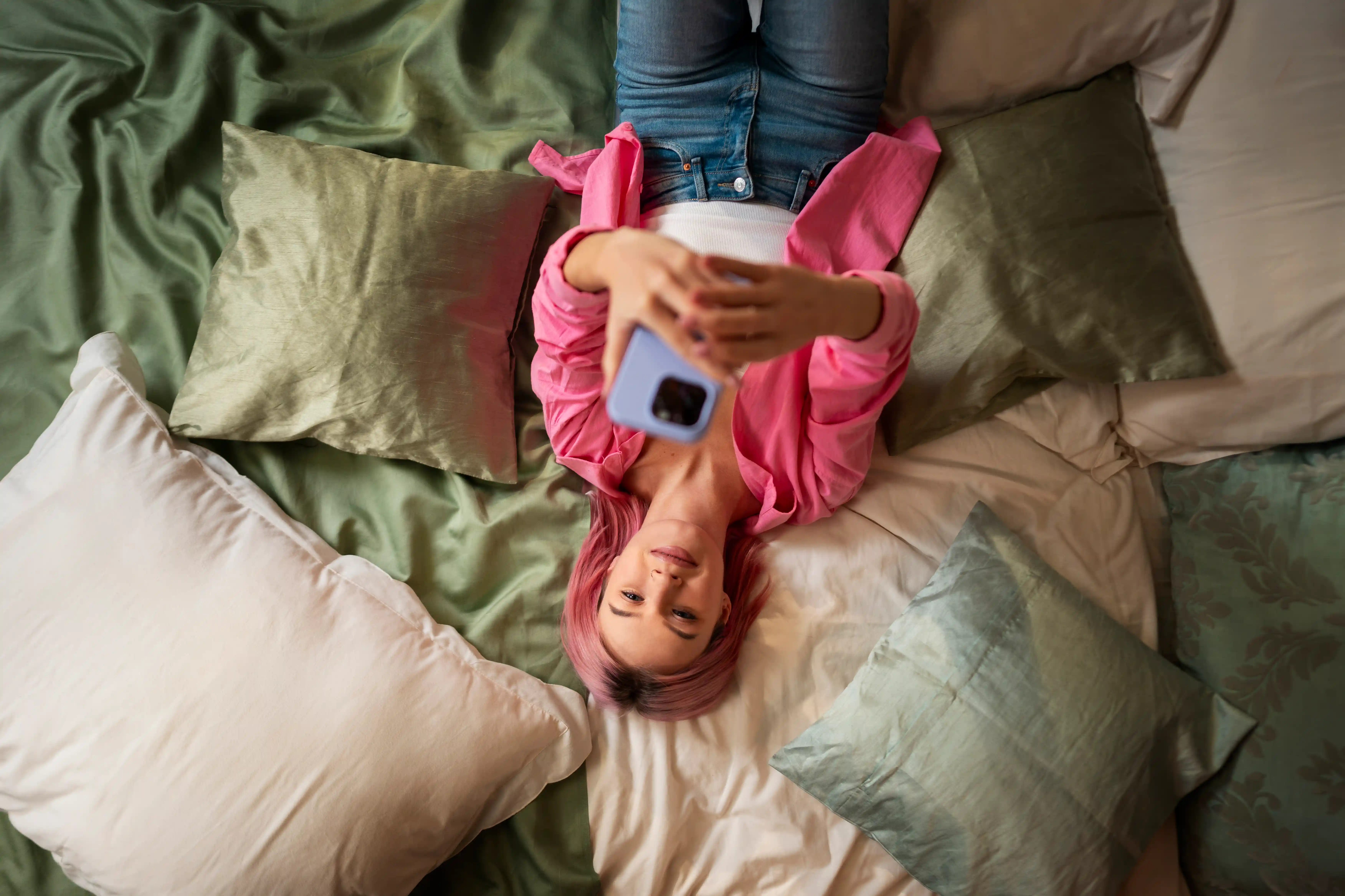 Woman in pink long sleeve shirt lying on bed