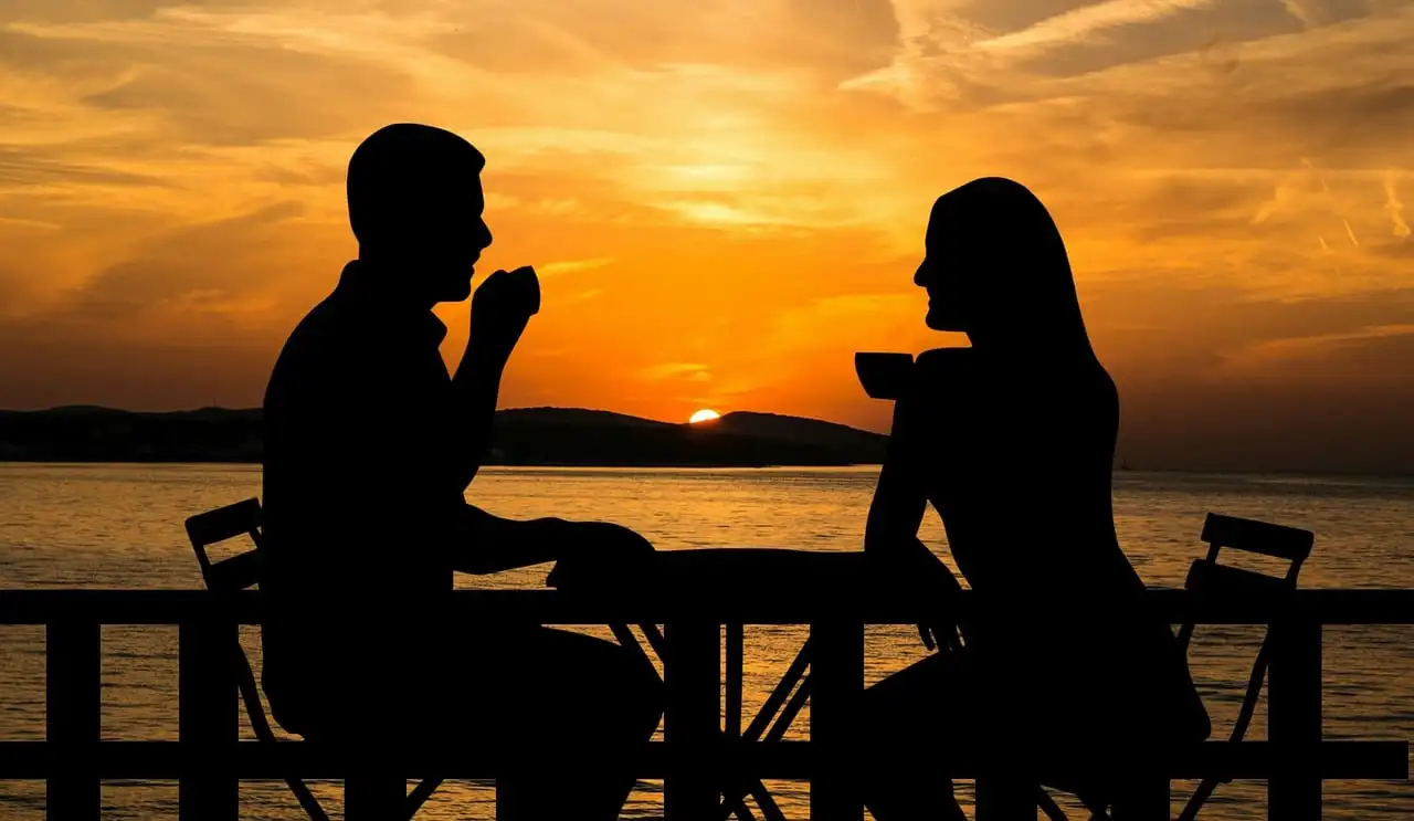 Man and woman sitting on chair in front of table during sunset